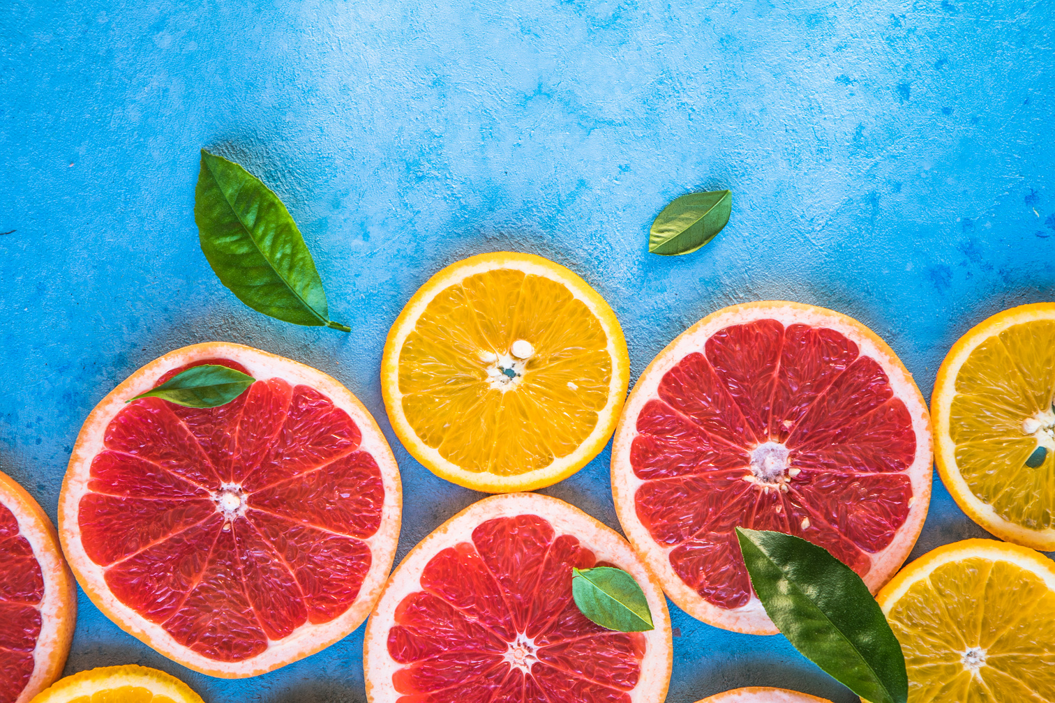 Vibrant colored citrus fruit on blue table